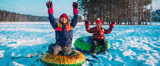 Two kids having fun tubing on a bright winter day