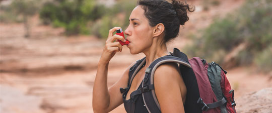 young ethnic female using her inhaler on a hike