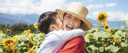 young mother hugging son in a sunflower field