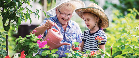 grandmother watering plants with young grandson