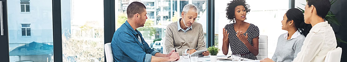 Business people having a discussion around table in front of a large window